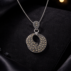 Silver necklace with a pendant on a black satin surface